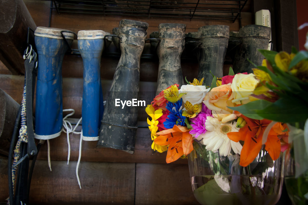 Flowers in vase against shoe rack at shop