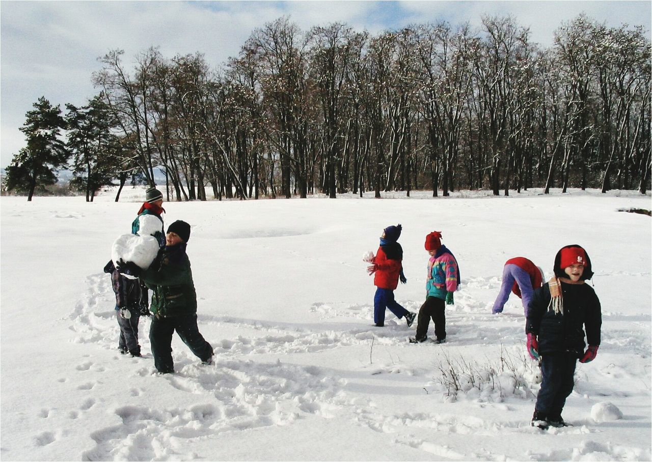 REAR VIEW OF CHILDREN PLAYING ON SNOWY FIELD