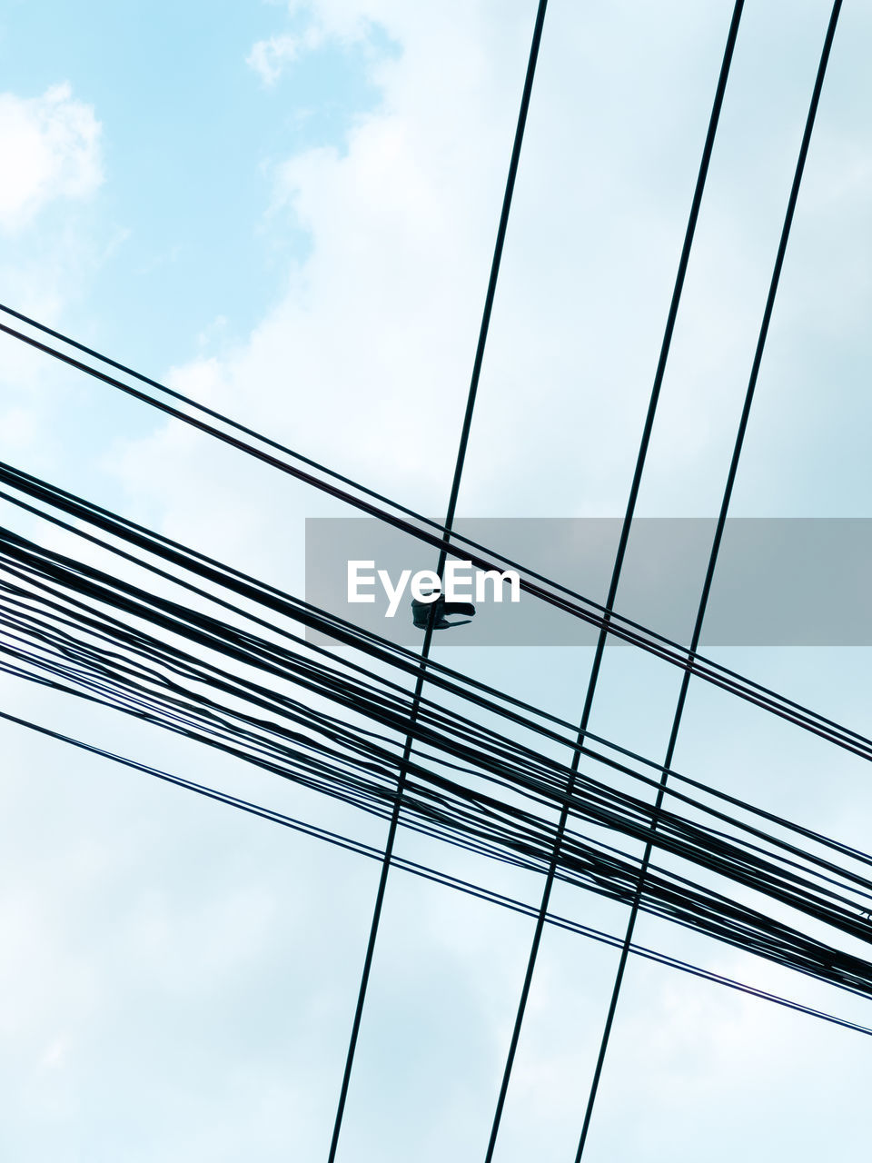 low angle view of cables against cloudy sky