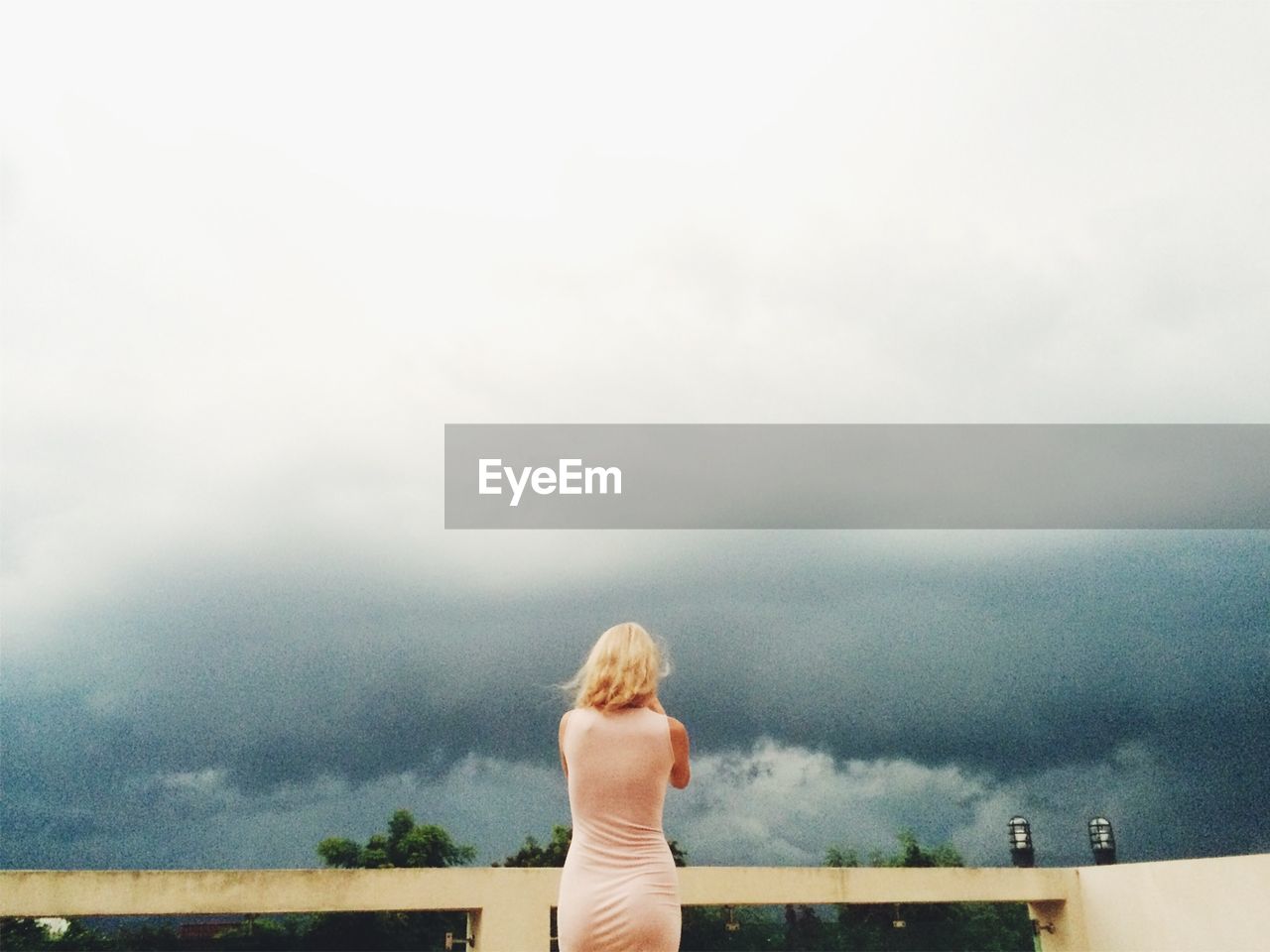 Rear view of woman standing against cloudy sky