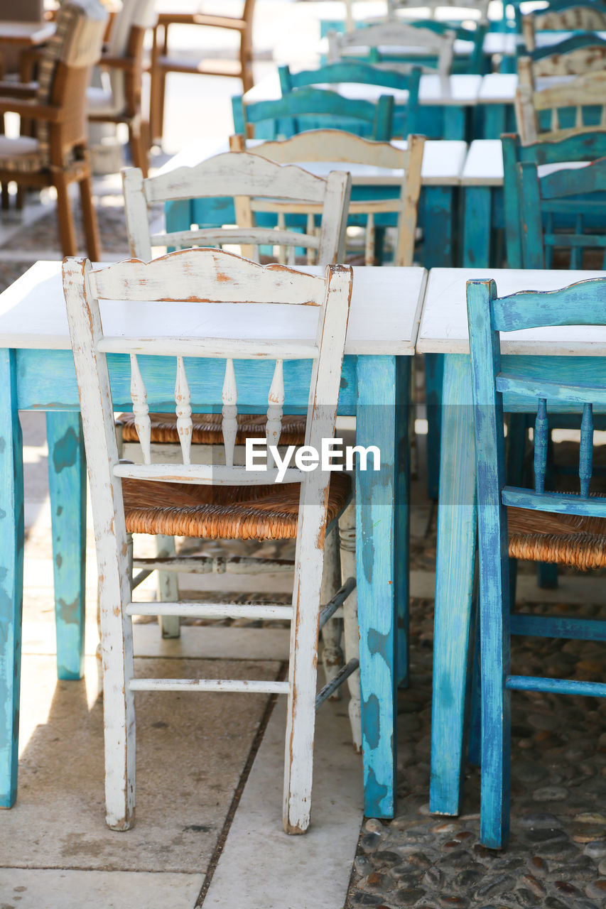 Empty chairs and tables in turquoise white brown and blue in row outdoors 