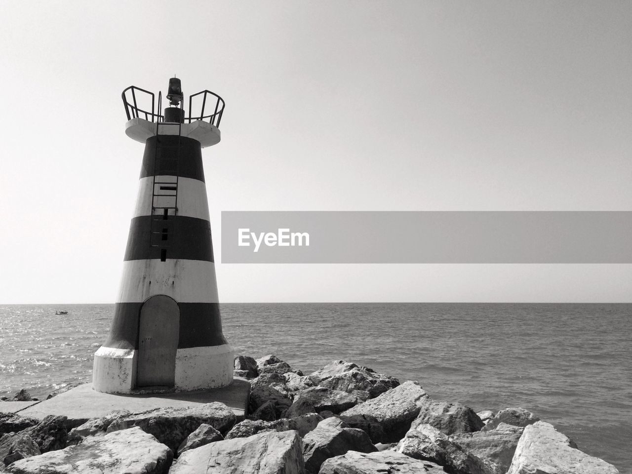 Lighthouse by sea against clear sky