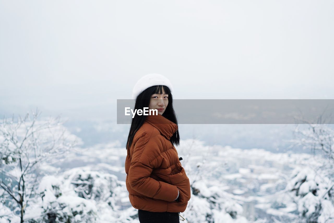 Portrait of woman standing on snow against sky