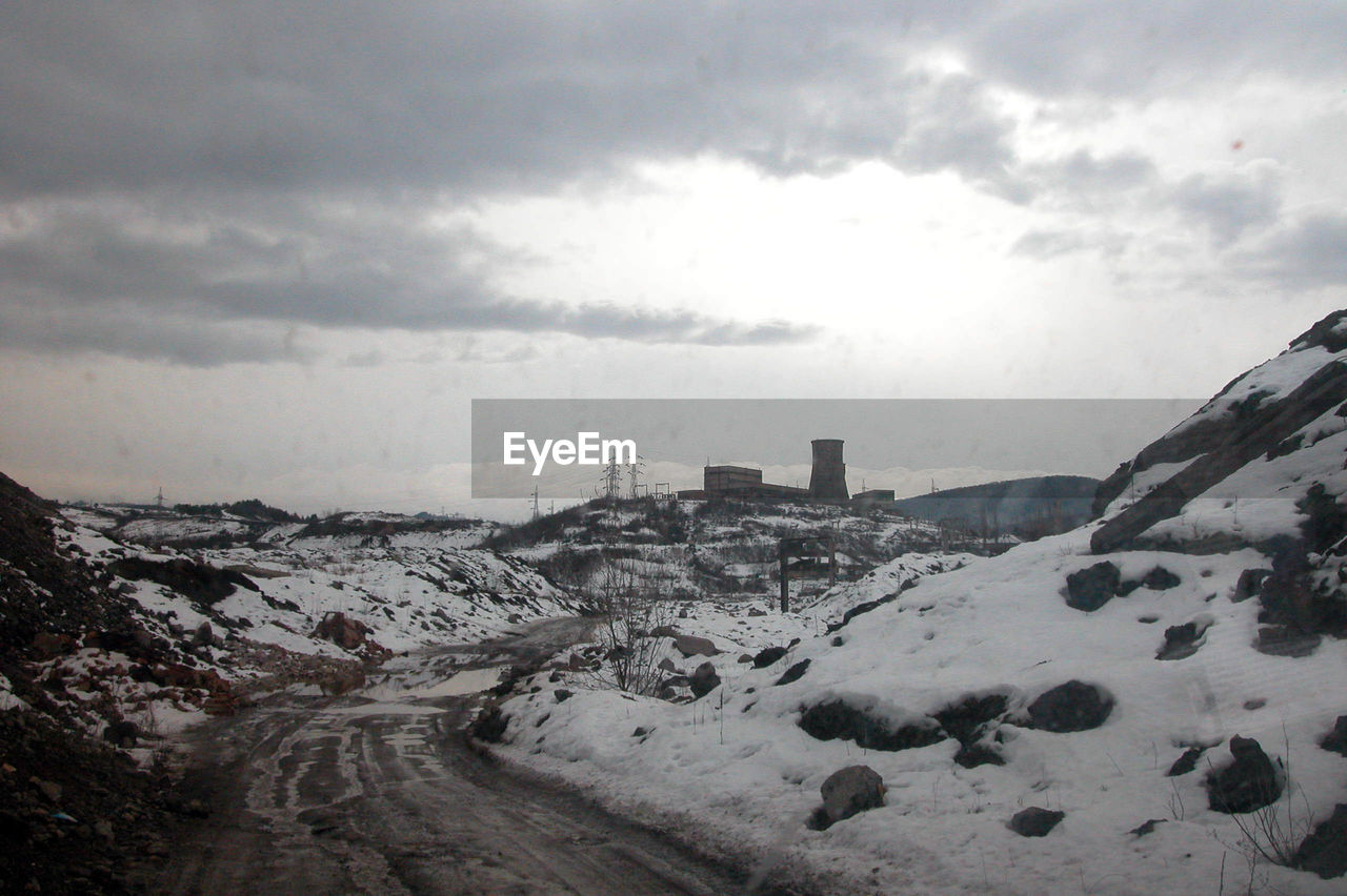 snow, cloud, sky, winter, environment, mountain, cold temperature, nature, landscape, scenics - nature, architecture, beauty in nature, no people, travel, travel destinations, outdoors, transportation, overcast, rock, built structure, land, dramatic sky, road