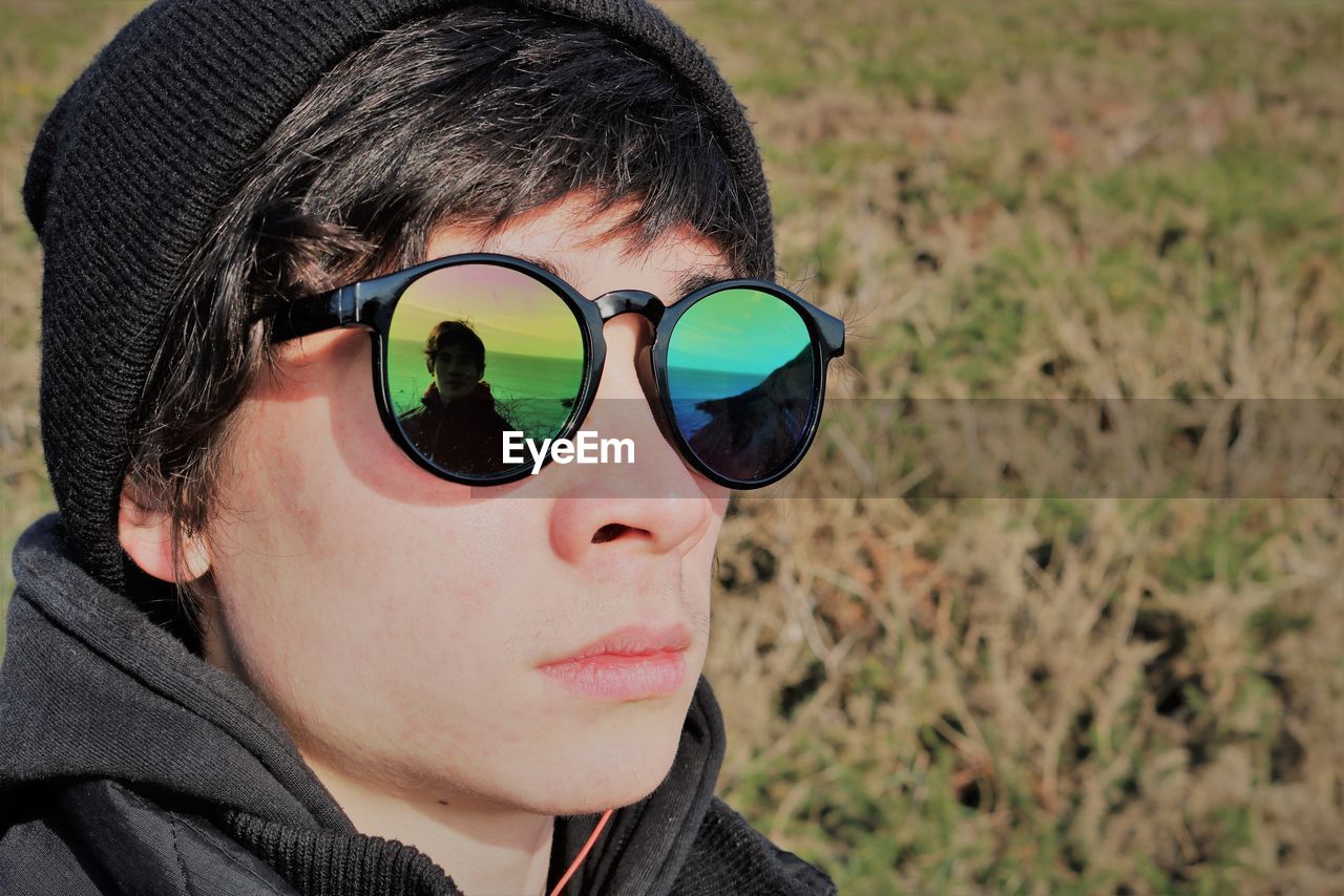 Close-up portrait of young man wearing sunglasses on field