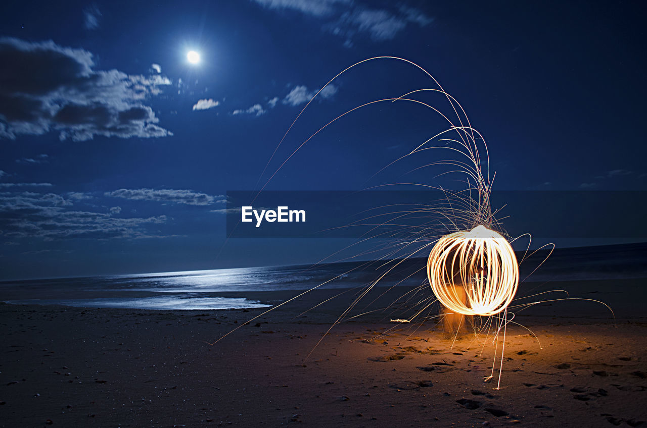 Burning steel wool firework on beach at night