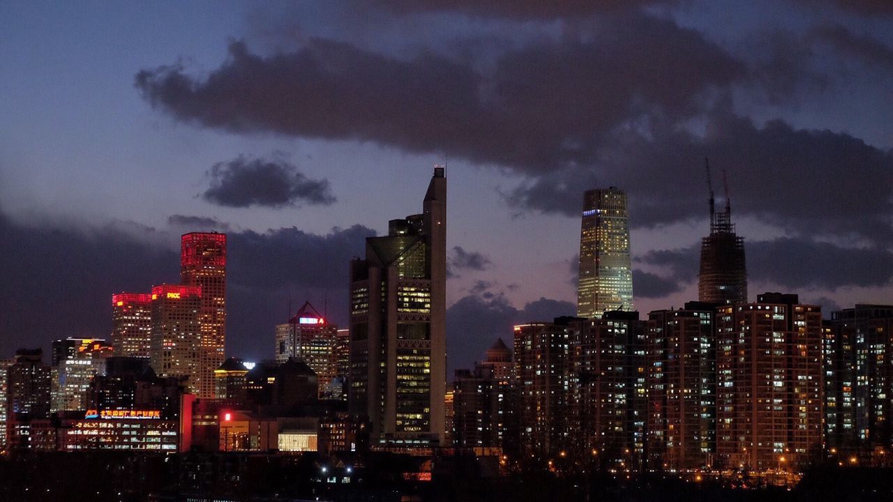 Illuminated cityscape against cloudy sky