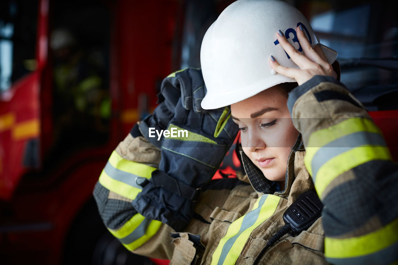 Female firefighter wearing helmet while looking down at fire station