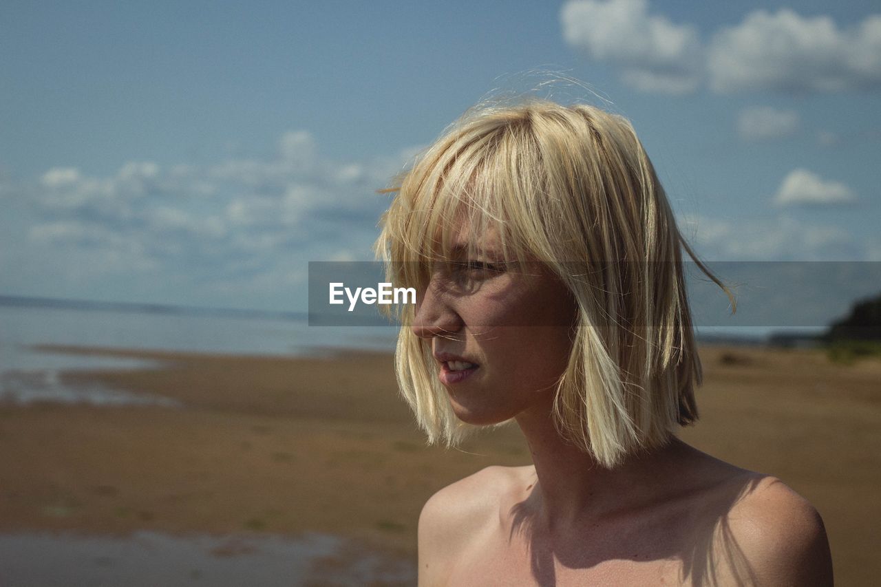 Close-up of young woman at beach against sky