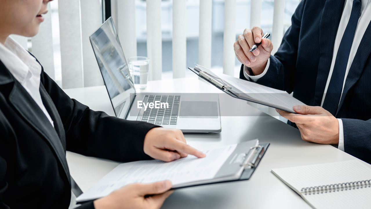 midsection of business people working on table