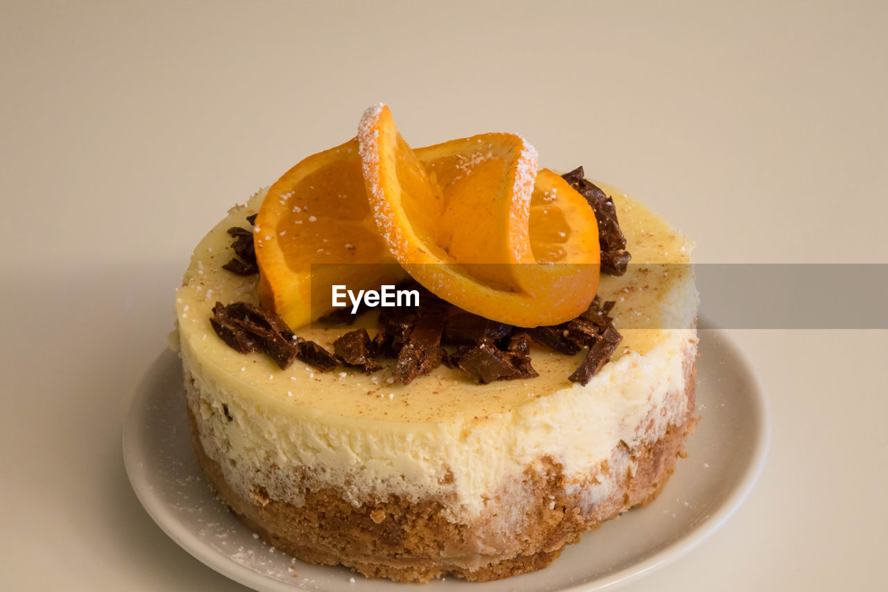 Close-up of cheesecake in plate on against beige background