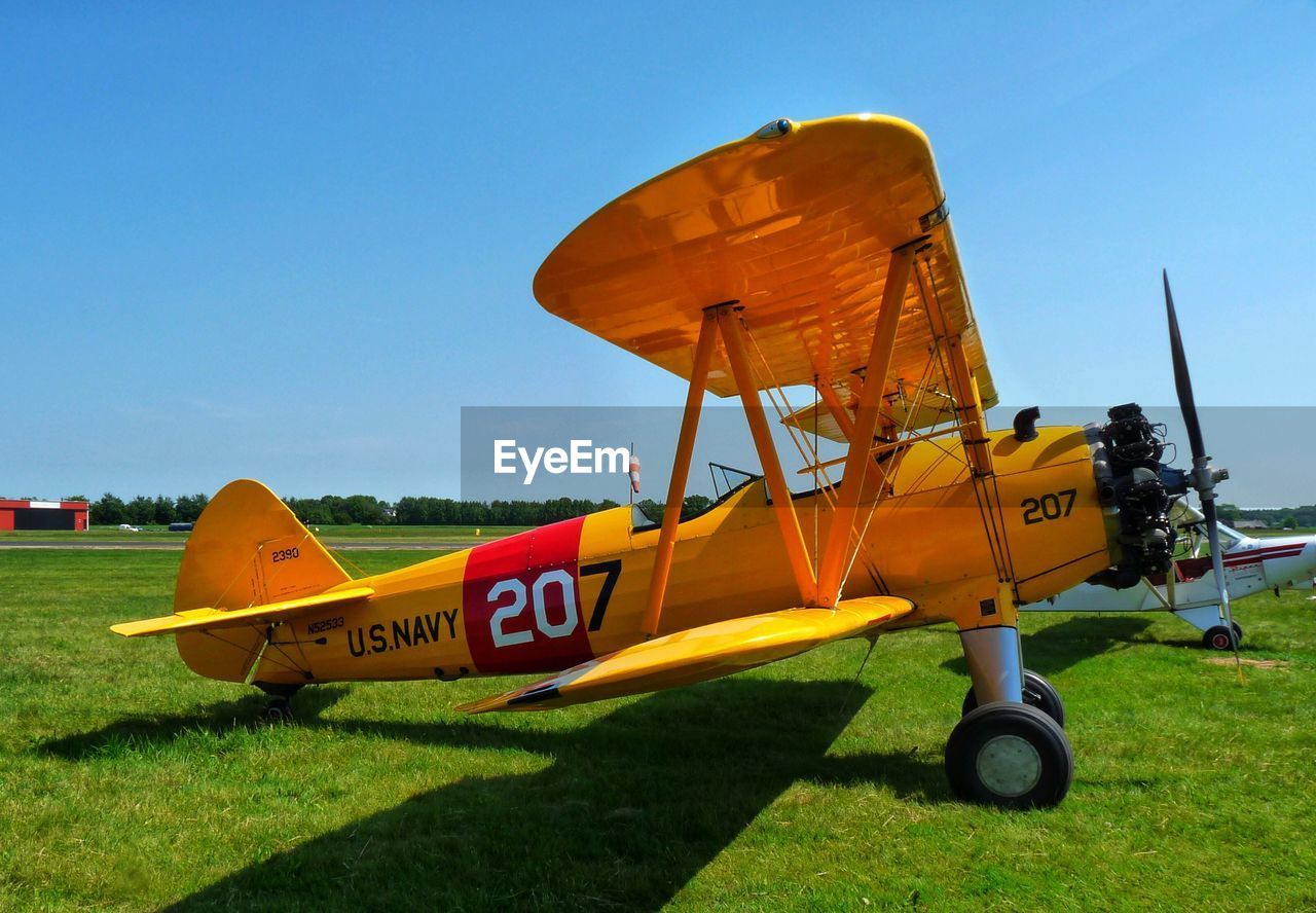 YELLOW AIRPLANE ON RUNWAY AGAINST SKY