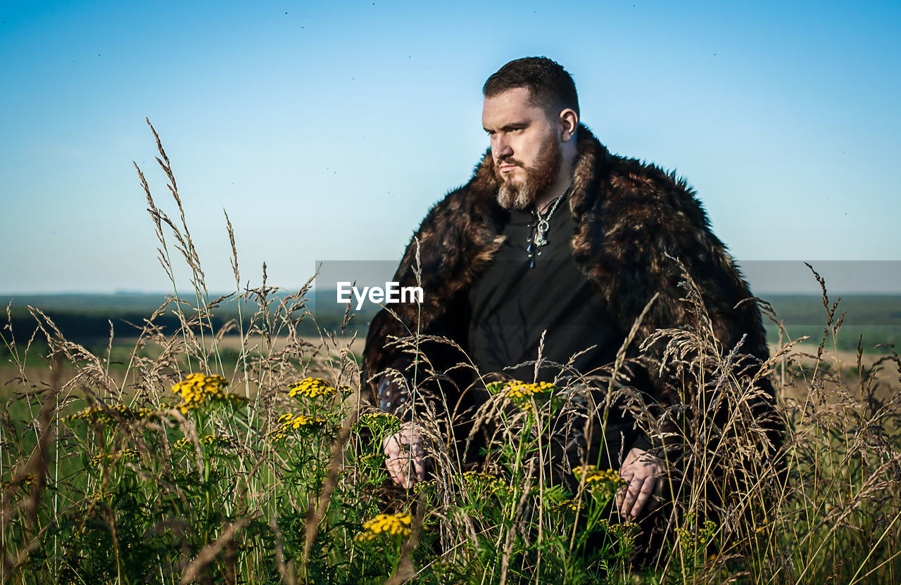 Hunter standing on grassy field against sky