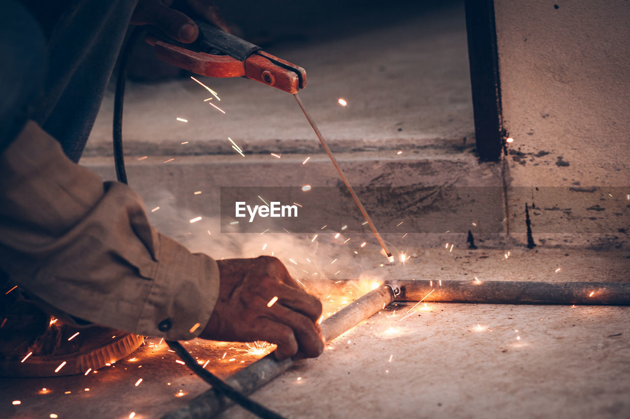 Cropped image of worker welding rods in factory