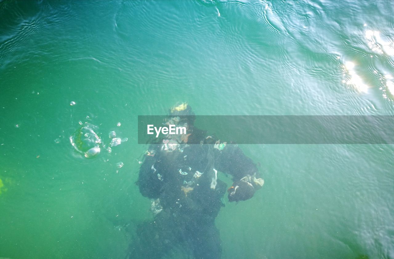 HIGH ANGLE VIEW OF MAN SWIMMING UNDERWATER
