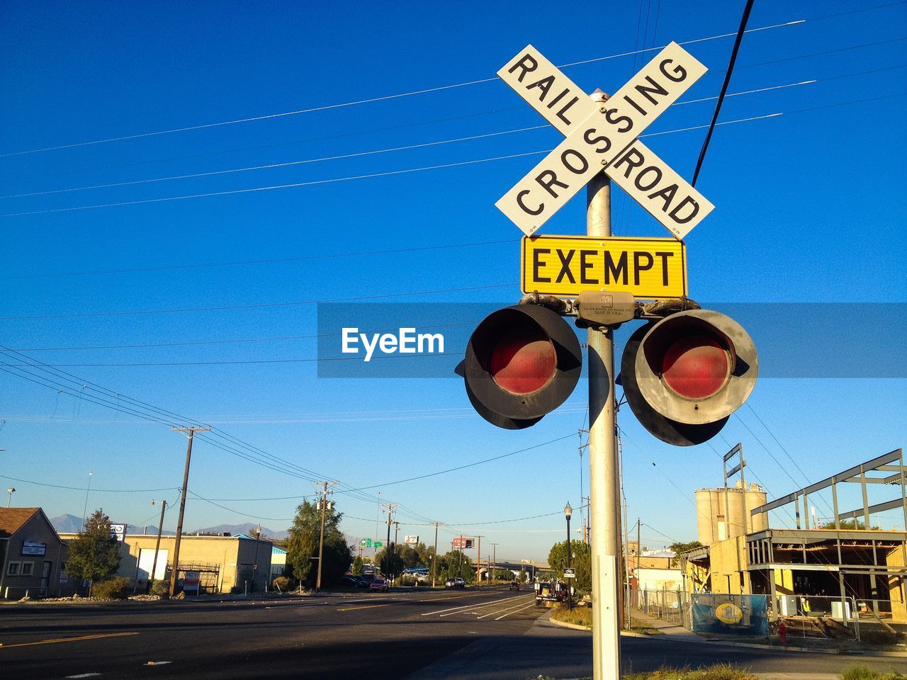 Low angle view of railroad crossing sign against blue sky