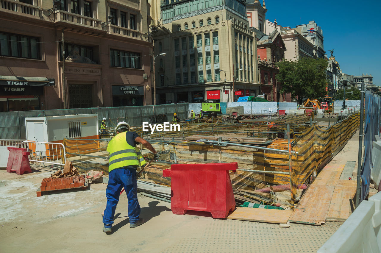 REAR VIEW OF MAN WORKING AT CONSTRUCTION SITE