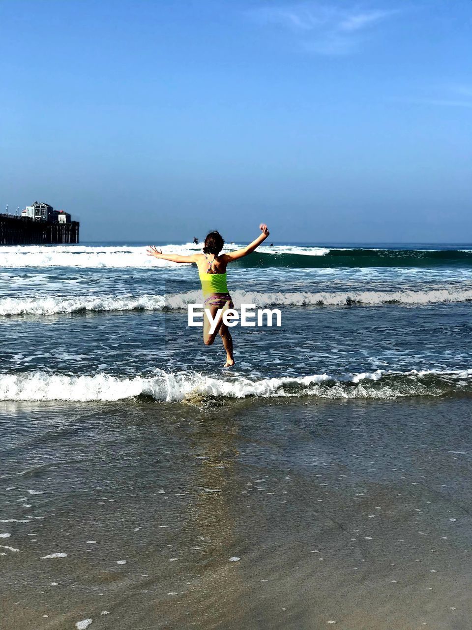 Woman running in sea against blue sky