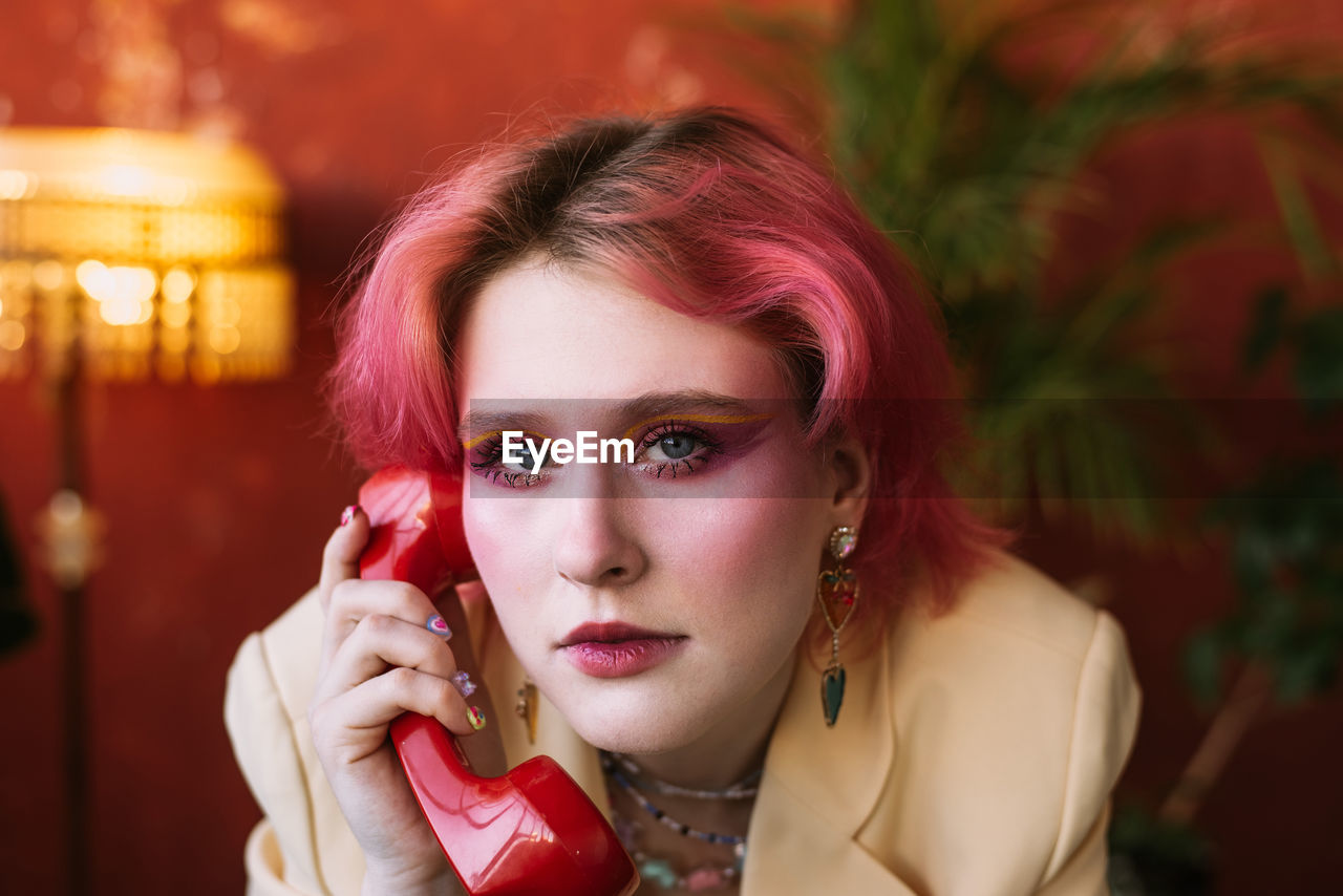 Young fashion woman posing with retro phone, bright make up and colored hair