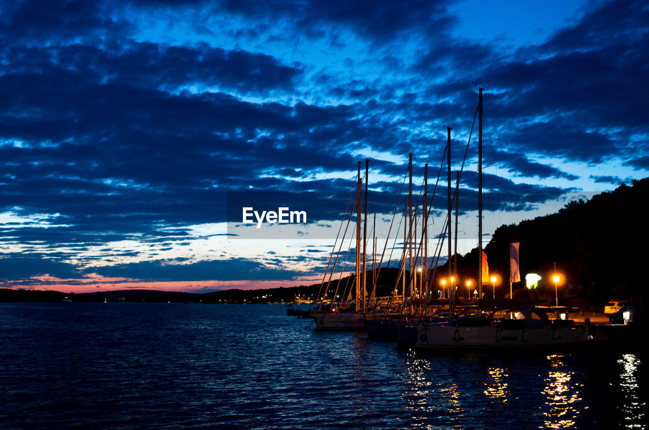 Sailboats in sea against sky at sunset