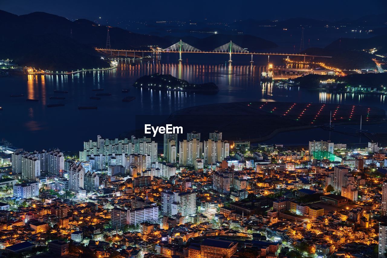 High angle view of illuminated city by buildings at night