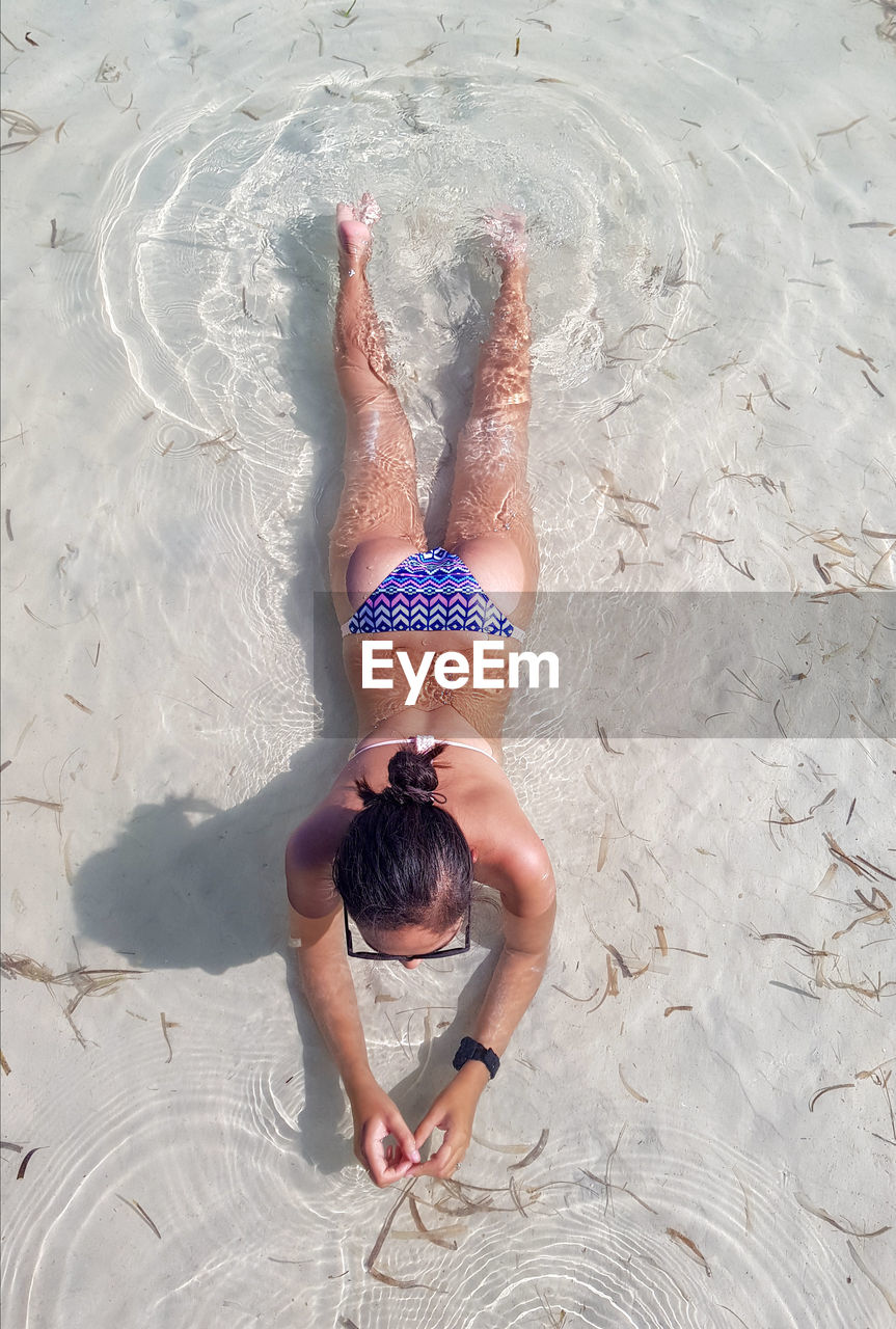 High angle view of woman in bikini lying on beach