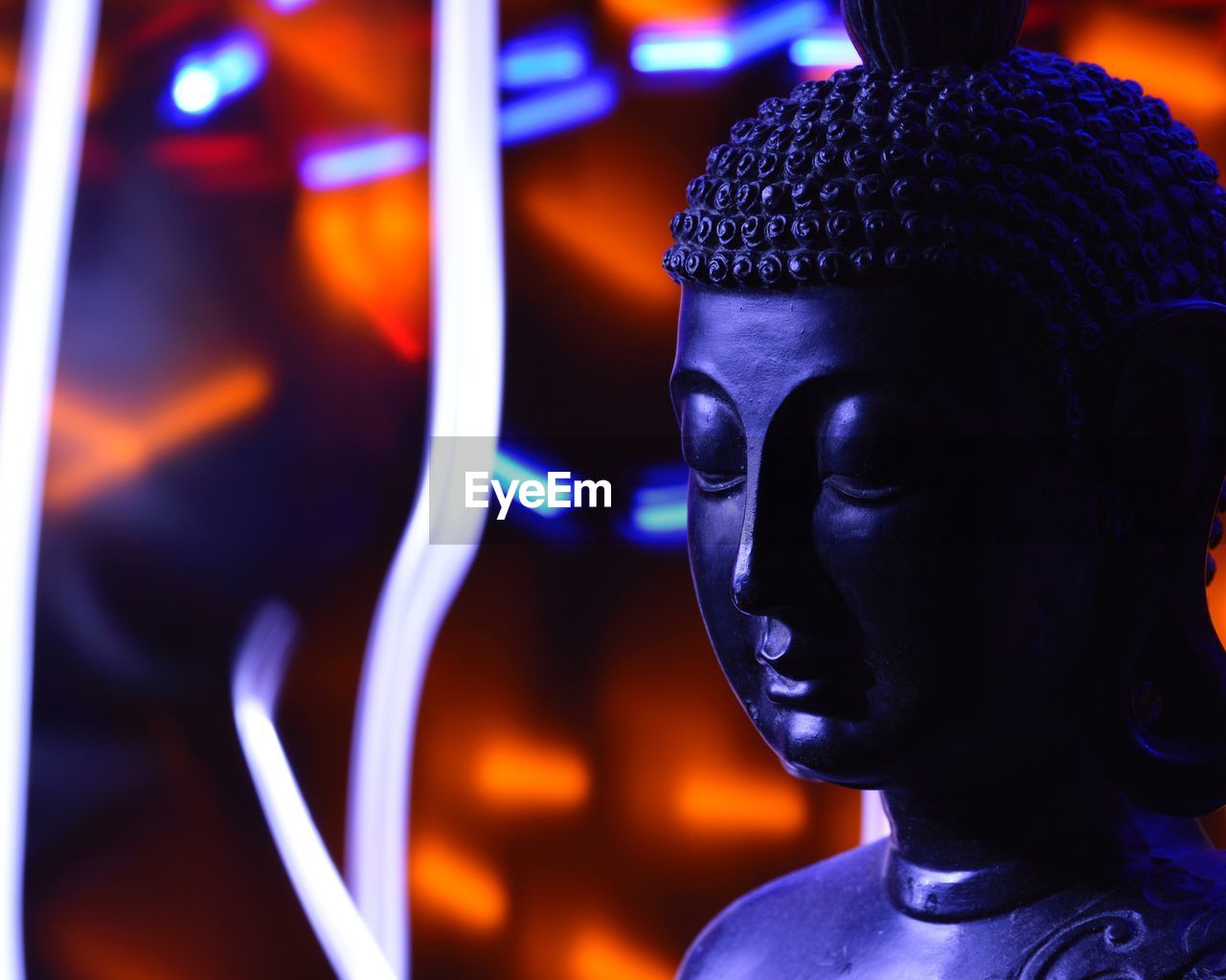 Close-up of buddha statue against illuminated abstract backgrounds