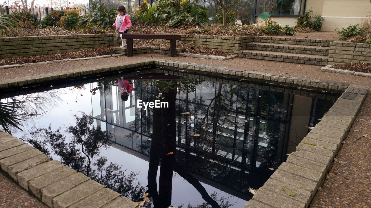 Reflection of girl and building in pond