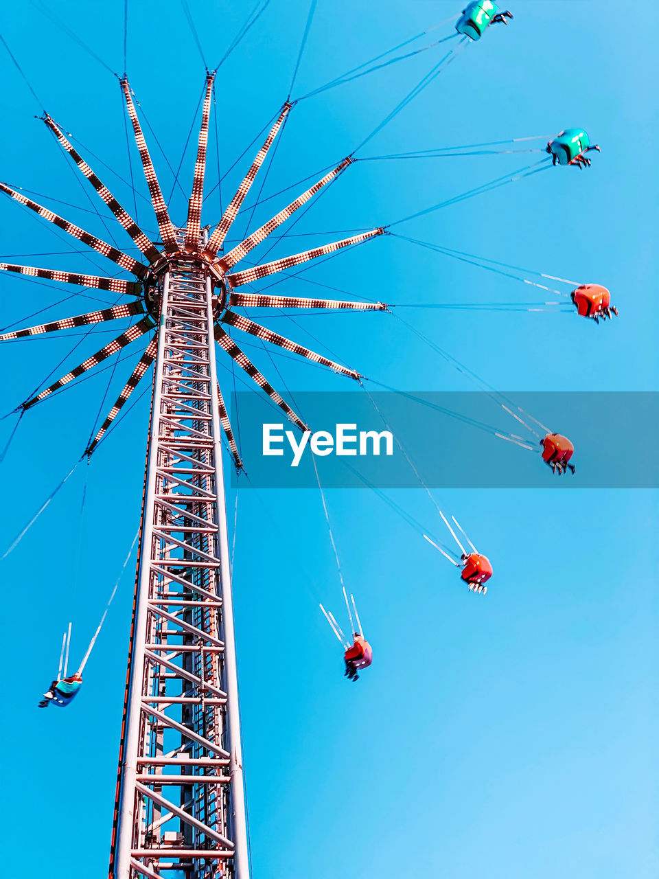 LOW ANGLE VIEW OF CHAIN SWING RIDE AGAINST BLUE SKY