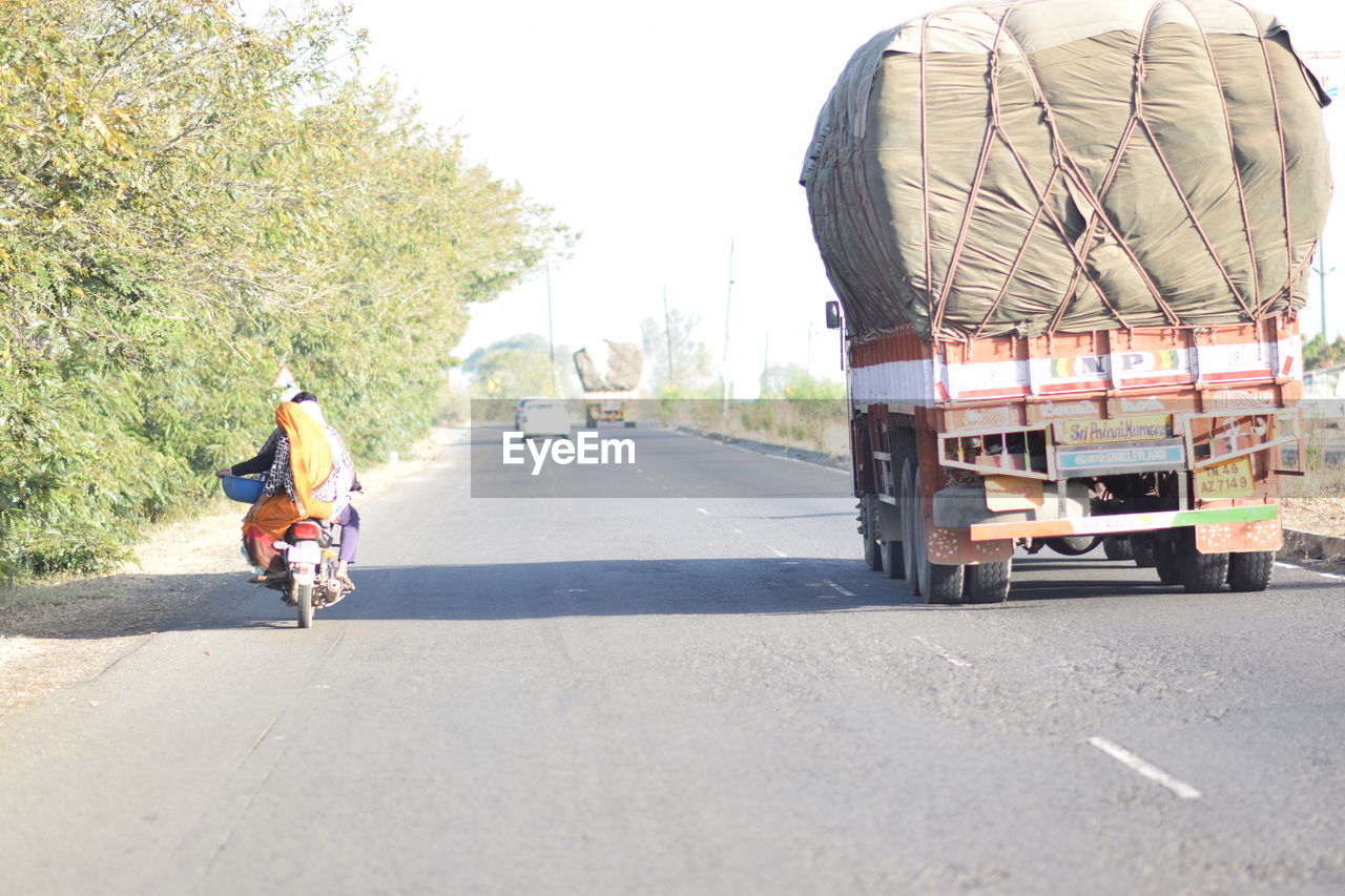 REAR VIEW OF MAN RIDING BICYCLE ON STREET