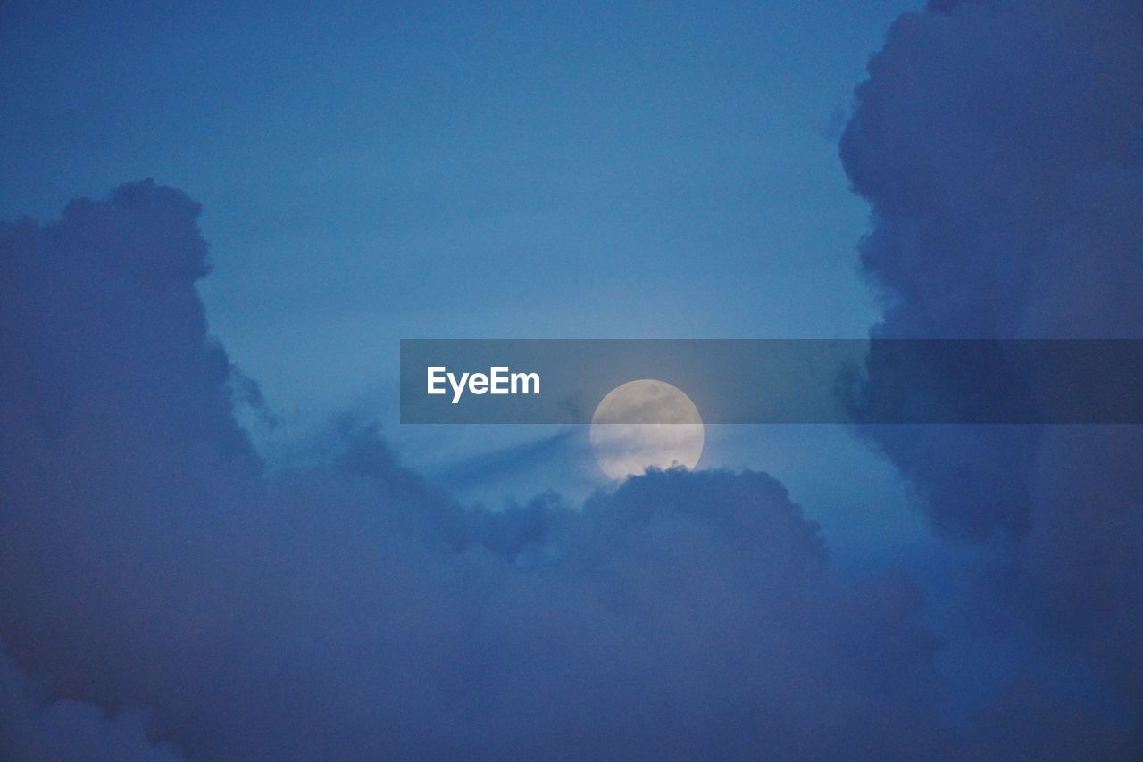 LOW ANGLE VIEW OF MOON AGAINST BLUE SKY