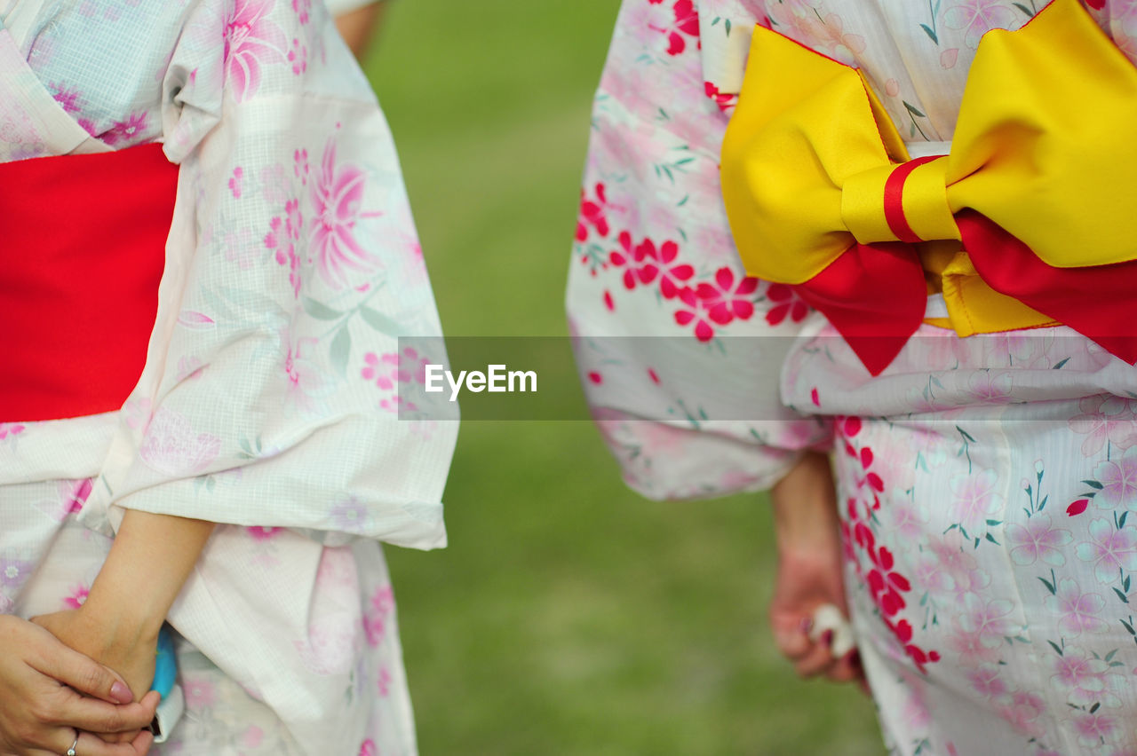 Midsection of women wearing kimonos on field