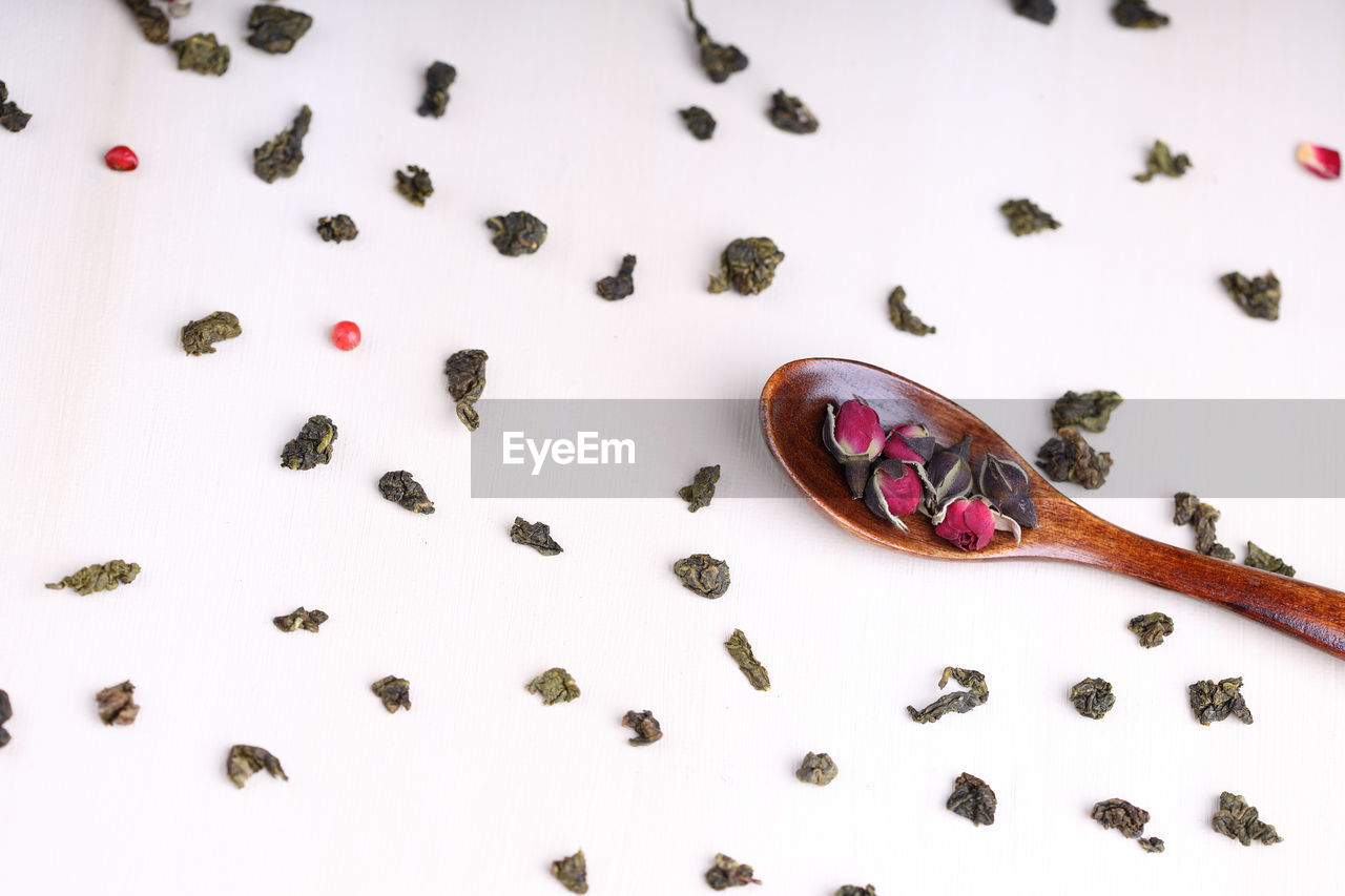 Green twisted tea leaves in clay cups with dried roses. chinese oolong is scattered on the table.