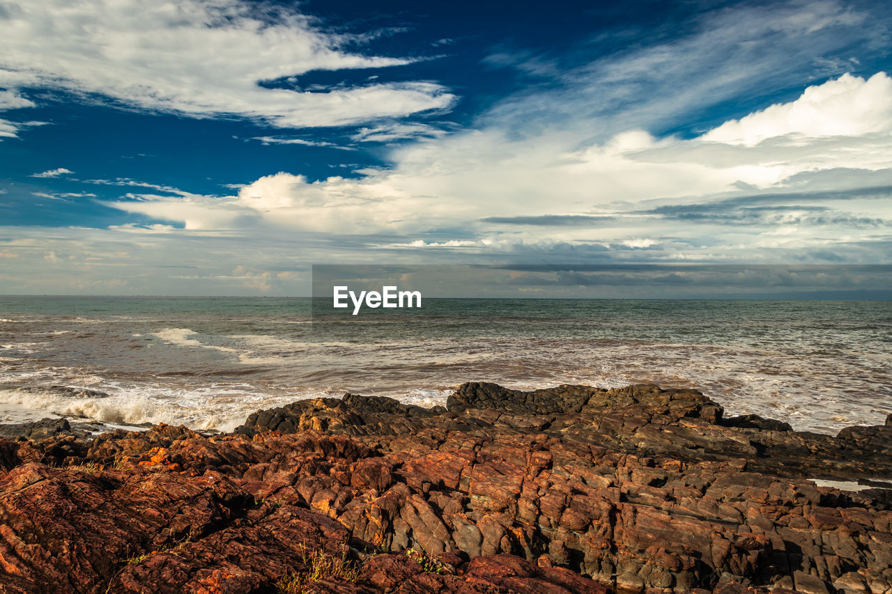 Rocky sea beach with crashing waves at morning from flat angle