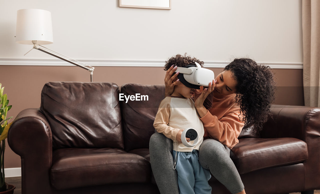 Mother helping son wearing virtual reality headset