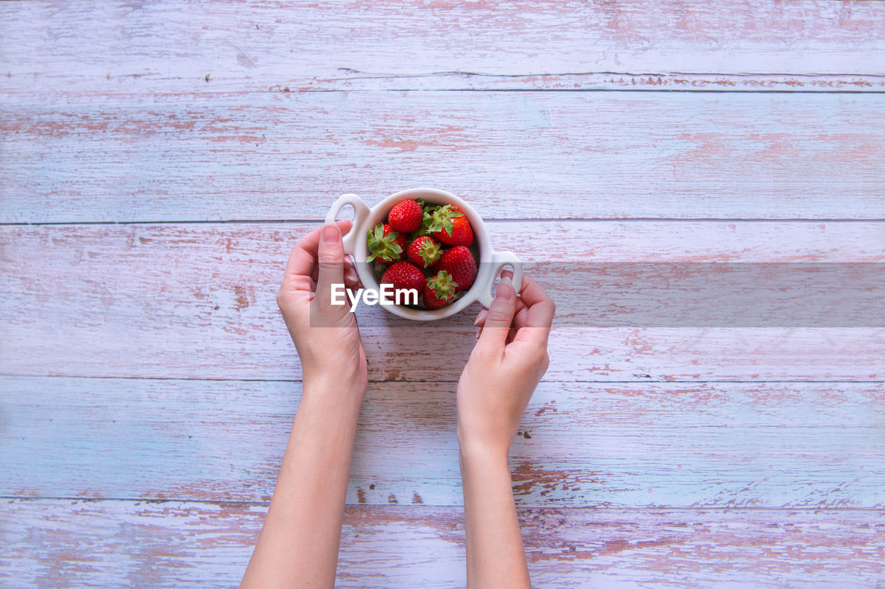 Directly above shot of hand holding fruit on table