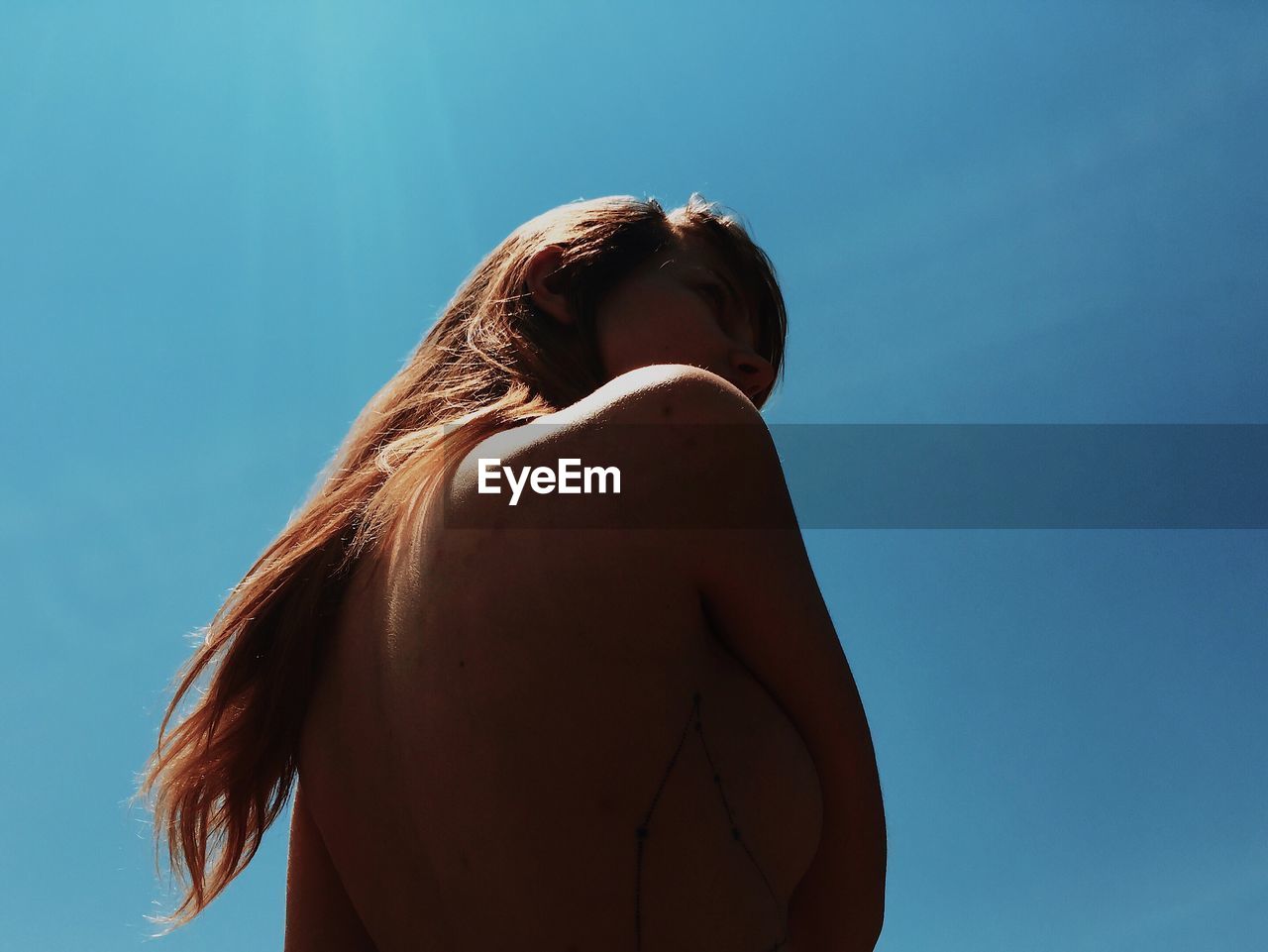 Low angle view of shirtless woman against clear sky