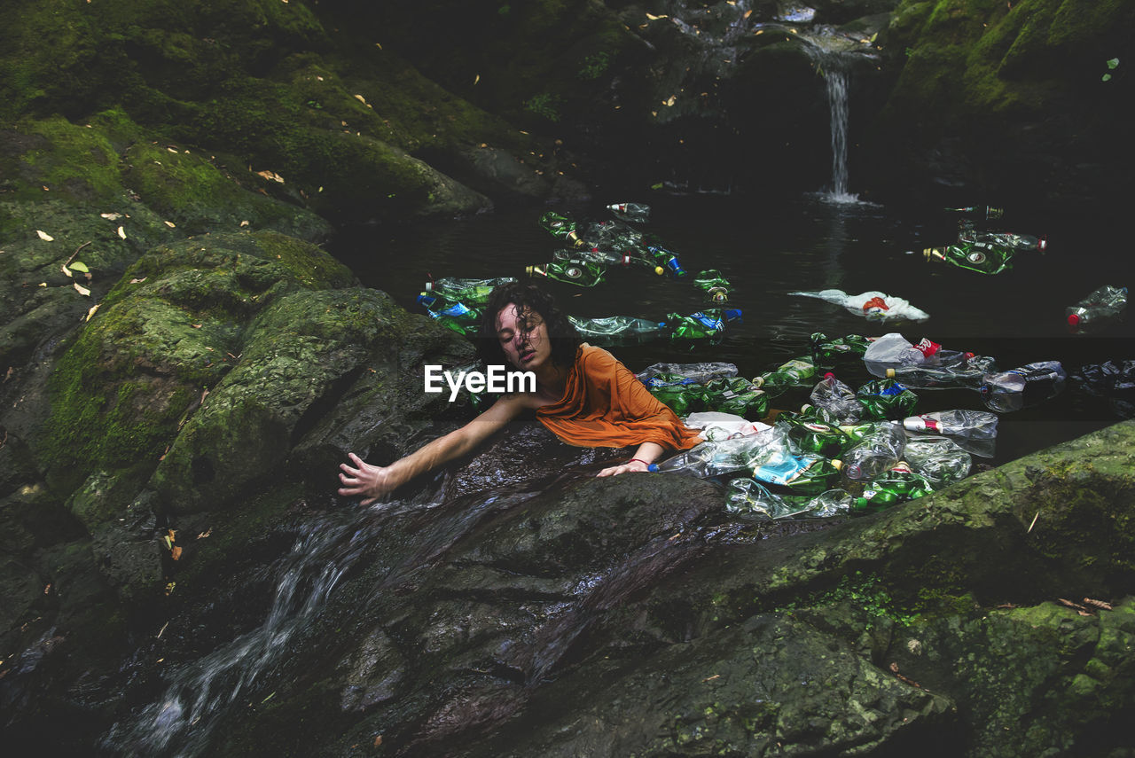 High angle view of woman amidst plastic bottles in water