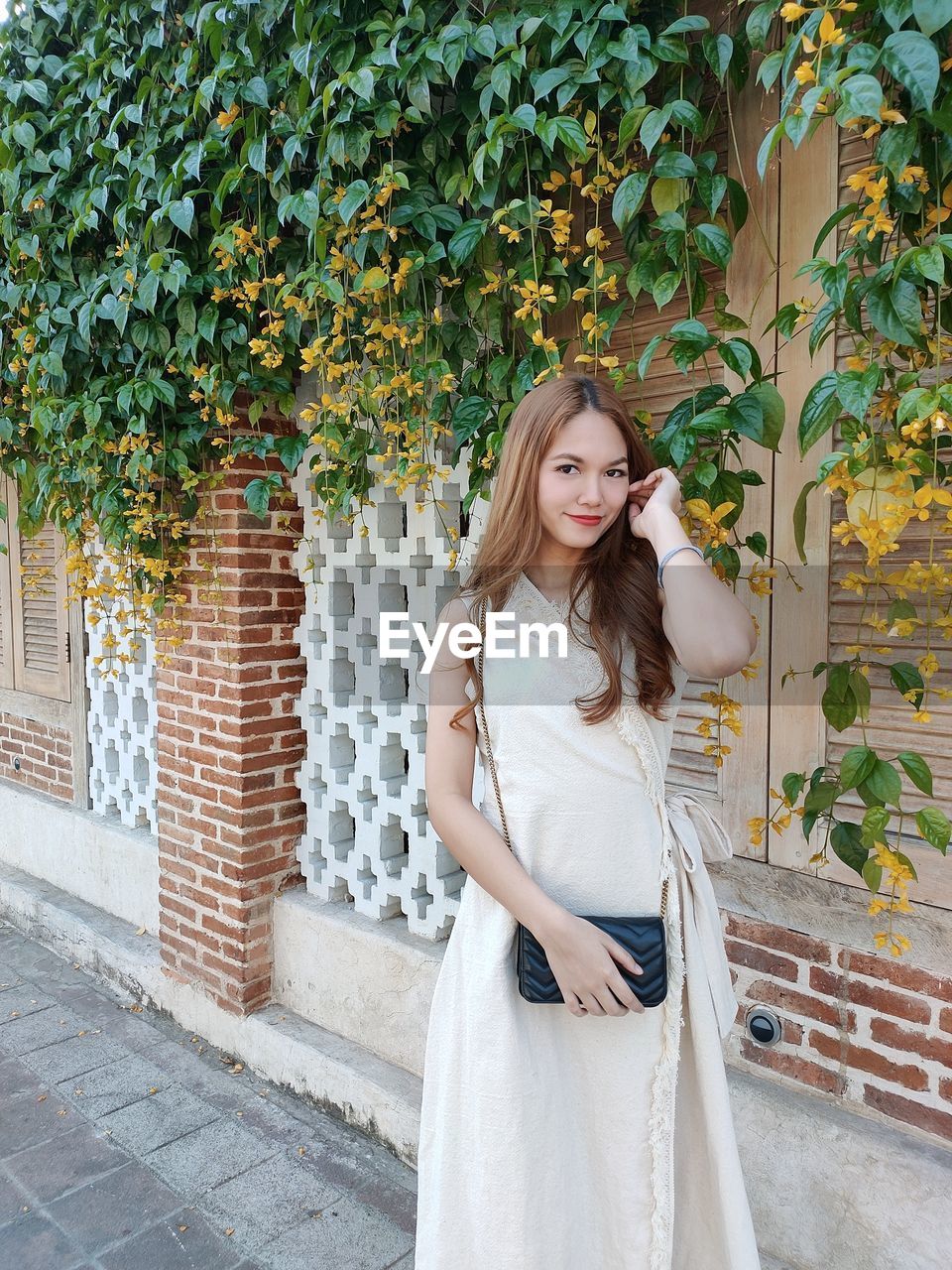 portrait of smiling young woman standing against trees