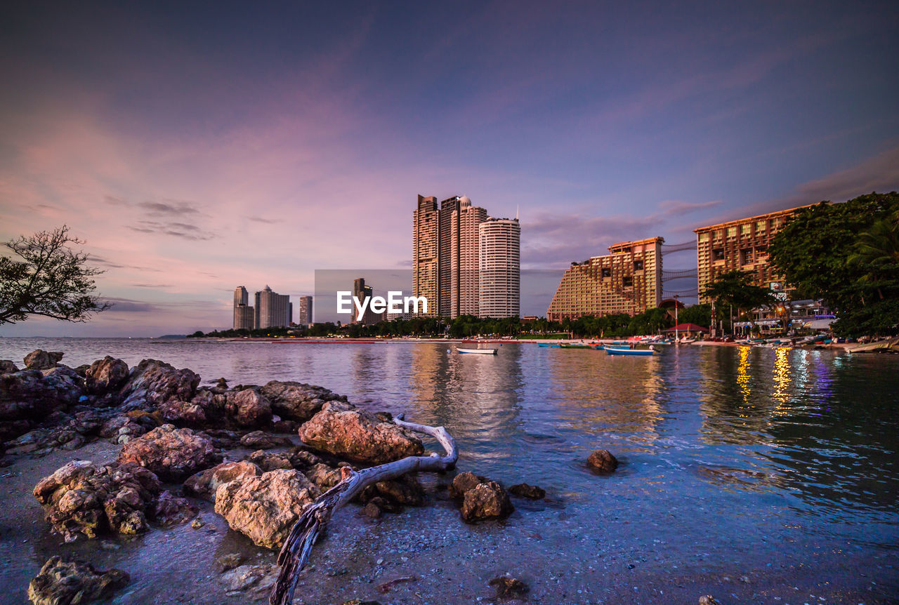 CITY BUILDINGS BY RIVER AGAINST SKY