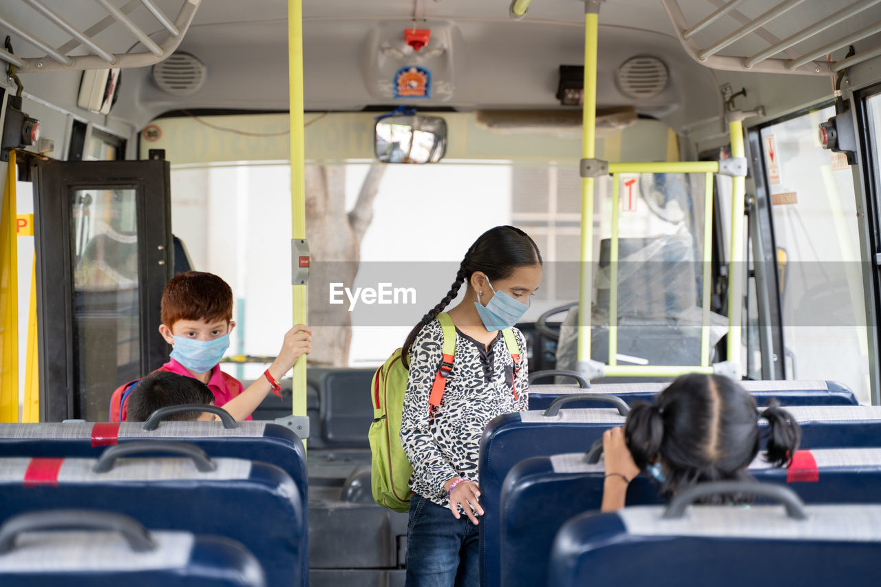 Cute girl wearing flu mask standing in bus