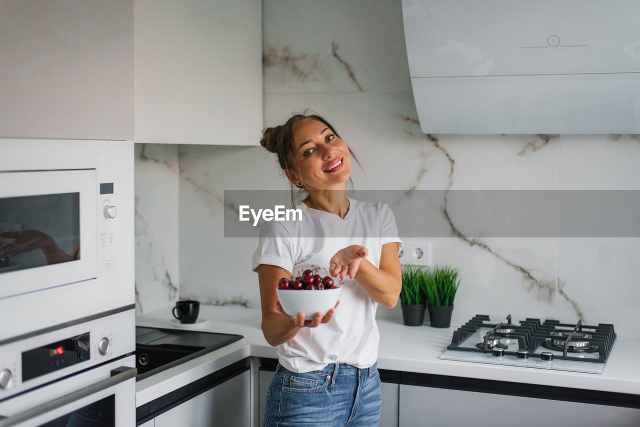 Happy nutritionist woman holds a fresh cherry berry in a plate in her hand. the concept of healthy