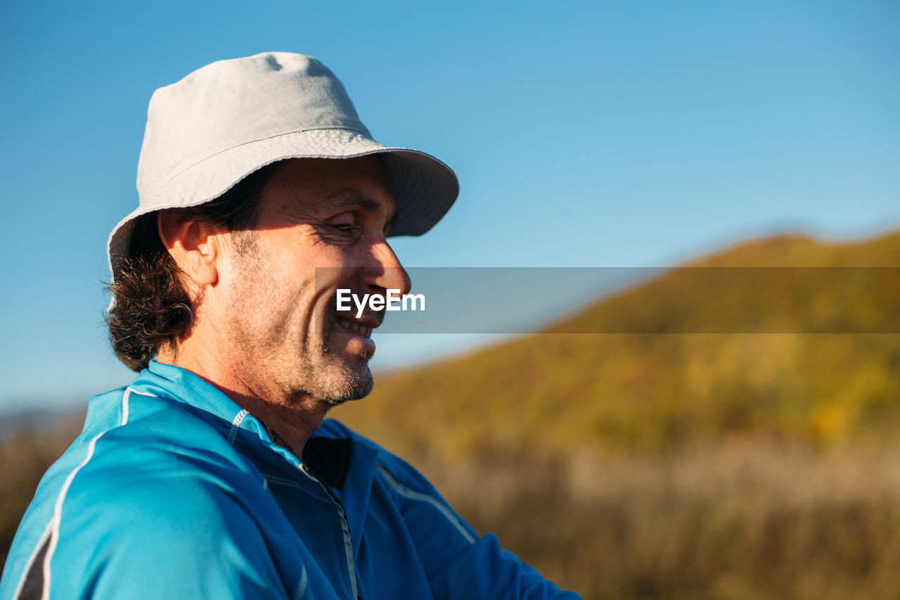 A profile shot of an older man. autumn mountains background