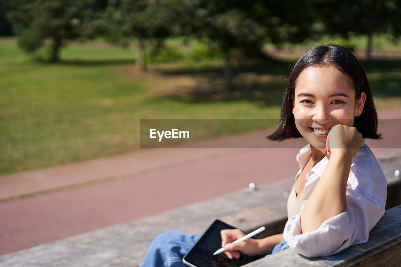 portrait of young woman sitting on footpath