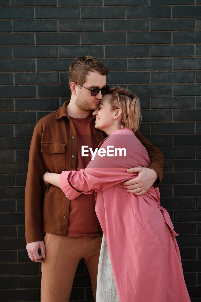 Couple hugging over dark wall. happy man and woman touching tender each other. love and romance