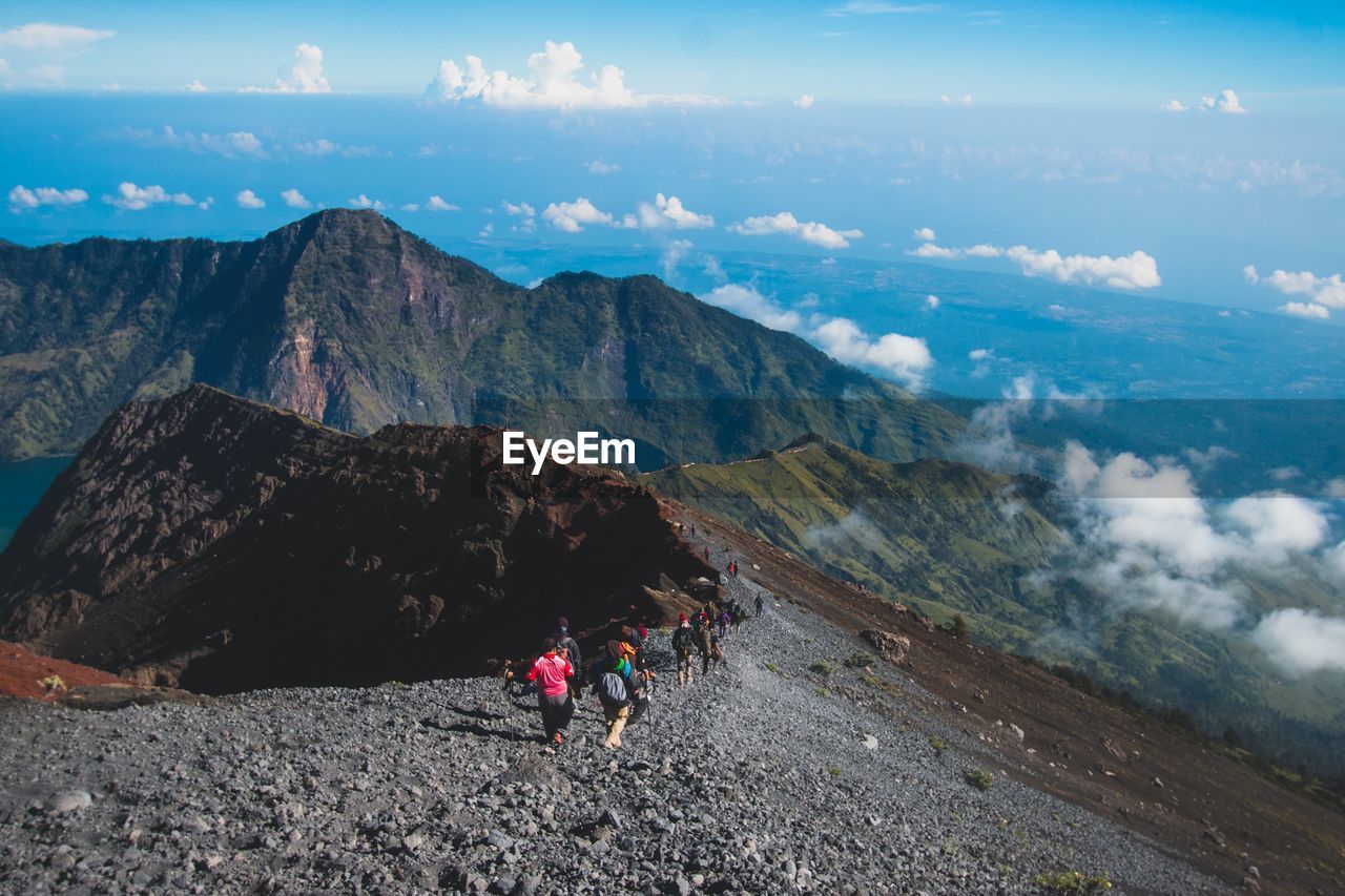 People hiking on mountains against sky