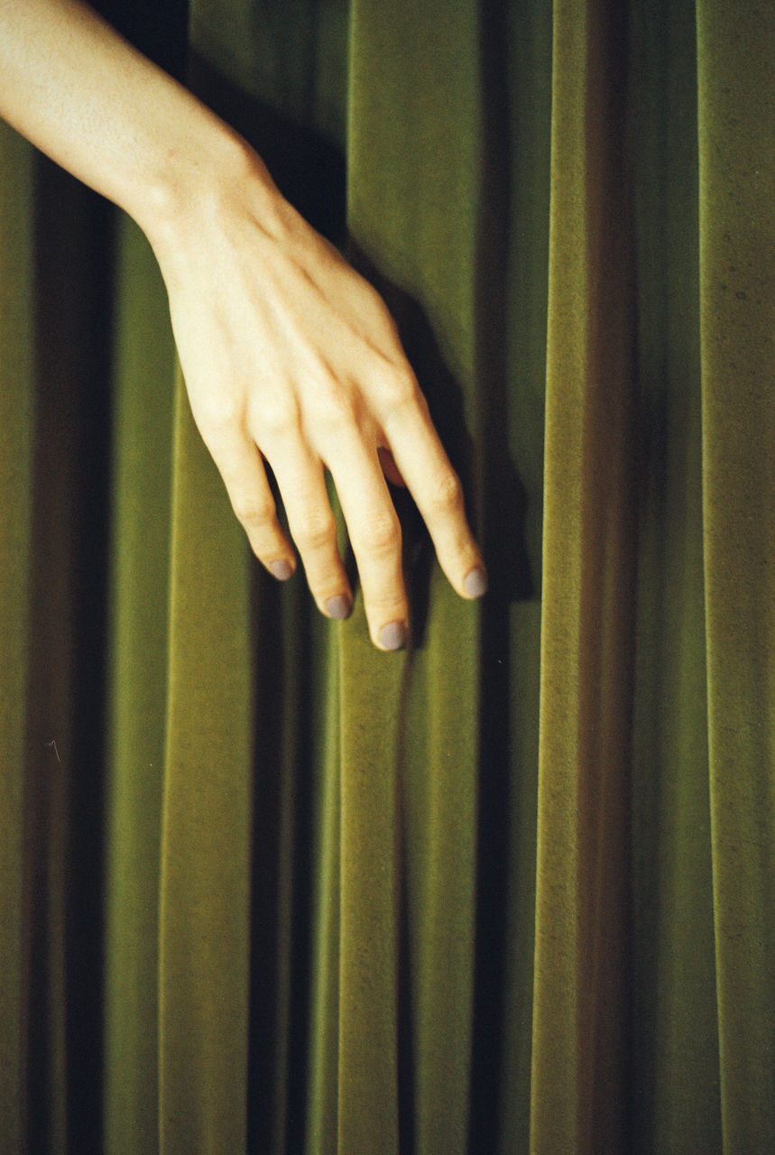 Cropped hand on green curtain