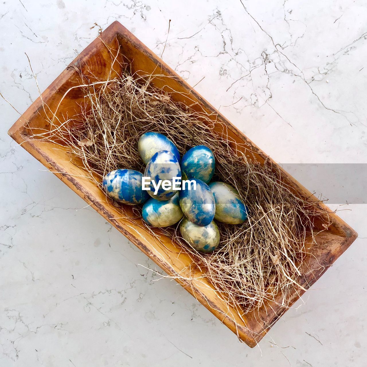 Directly above shot of easter eggs and hay in container on table