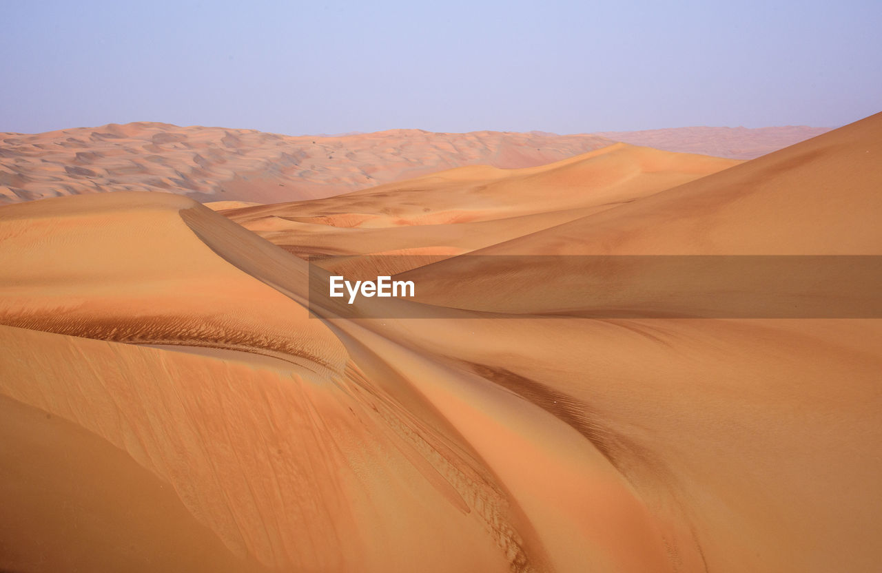 Scenic view of sand dunes in desert against clear sky