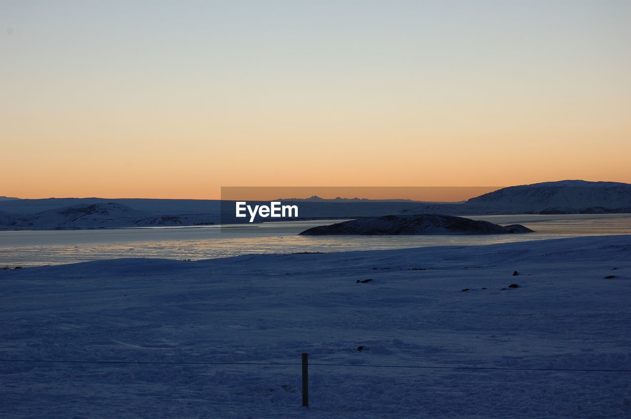 Scenic view of snowcapped icelandic mountains against clear sky during sunset